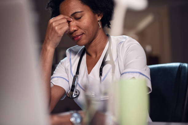 istock Black female nurse having a headache while working late. 1136935414