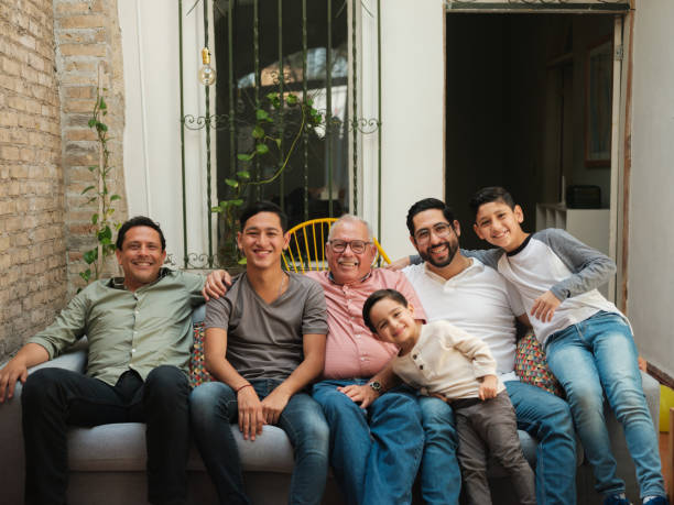 Mexican men and boys sitting together on sofa Mexican men and boy sitting together on the sofa, looking at the camera and smiling. mexican ethnicity photos stock pictures, royalty-free photos & images
