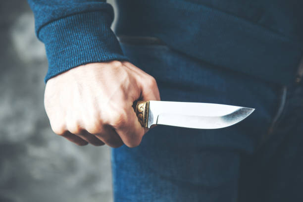 istock man hand knife on dark background 1136937918