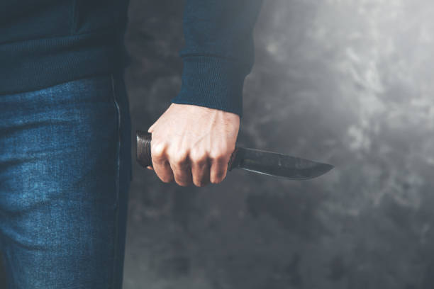 istock man hand knife on dark background 1136937922