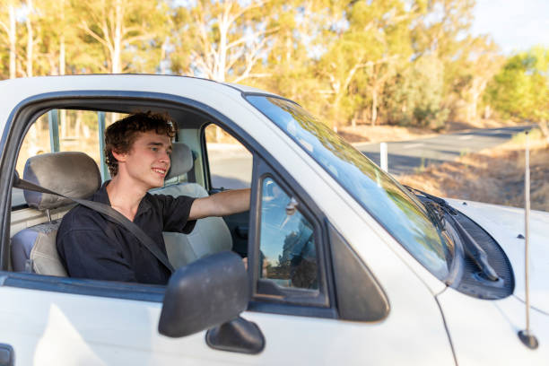 istock Young Man Driving a Car on a Dirt Farm Road 1136938705