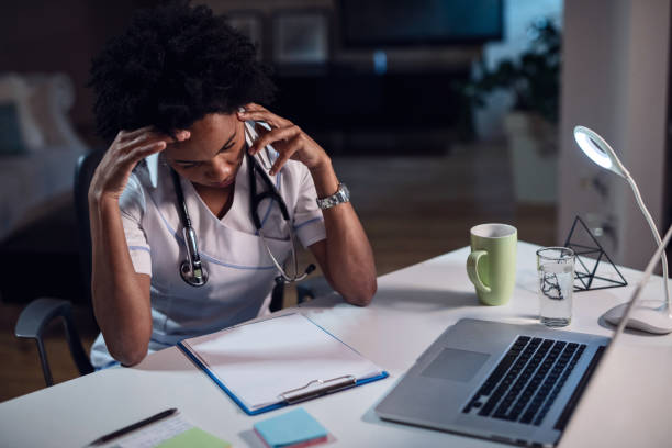 istock Black female doctor talking on the phone while reading medical record. 1136939049