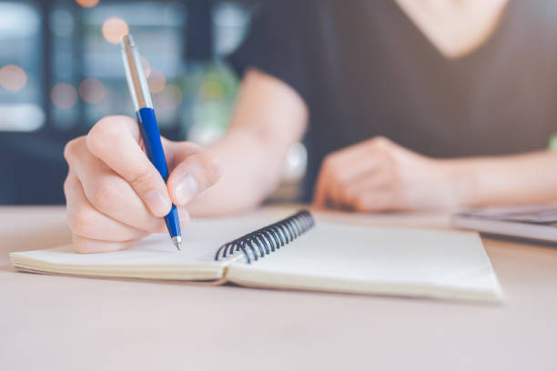 istock Woman hand is writing on a notebook with a pen. 1136945011