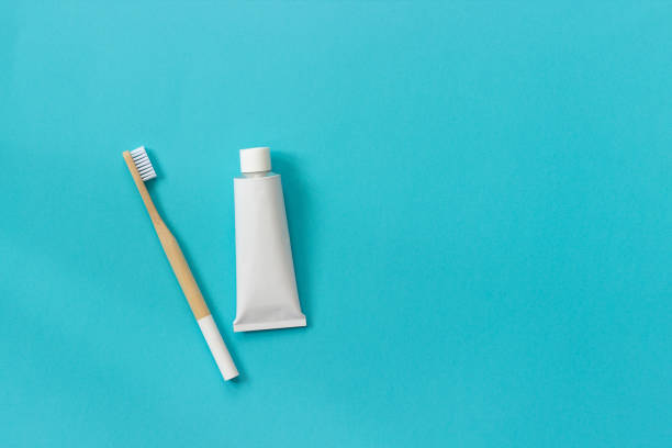 Natural eco-friendly bamboo brush with white bristles and tube of toothpaste. Set for washing on paper blue background. Copy space for text or your design Top view Flat lay Natural eco-friendly bamboo brush with white bristles and tube of toothpaste. Set for washing on paper blue background. Copy space for text or your design Top view Flat lay. toothbrush stock pictures, royalty-free photos & images
