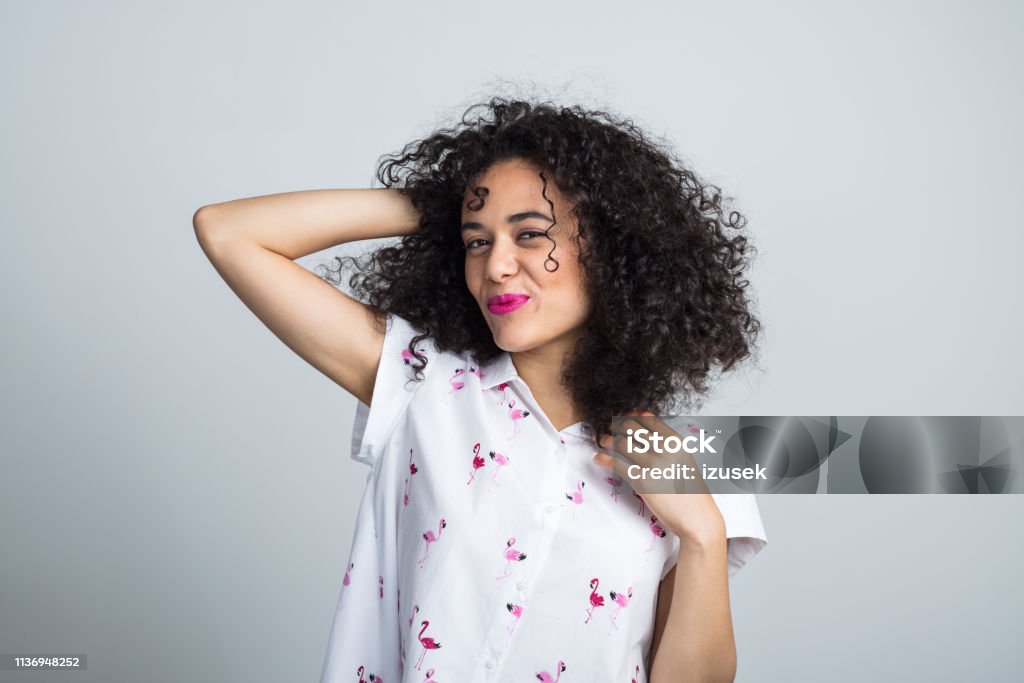 Beautiful woman posing on gray background Portrait of beautiful young woman with curly hair posing on gray background 20-24 Years Stock Photo