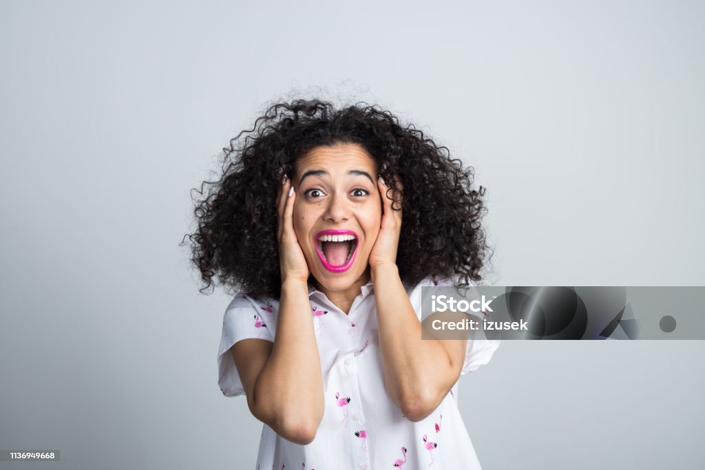 Attractive woman feeling excited Portrait of young attractive woman feeling excited on gray background. Female with hands on face shouting in joy. 20-24 Years Stock Photo