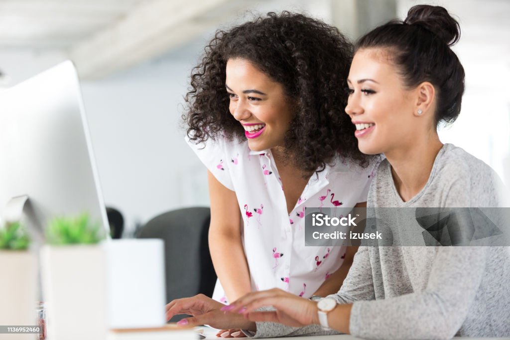Computer programmer discussing new coding Two beautiful young woman working together on a new software development in office. Computer programmer discussing new coding at desk working together. IT Support Stock Photo