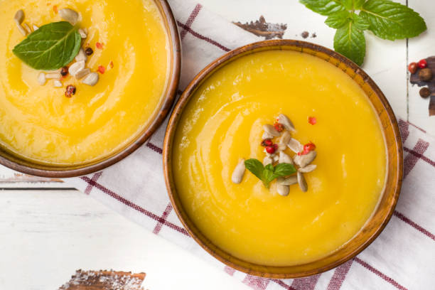 istock Pumpkin soup mashed with spices in wooden bowls on light boards. 1136953487