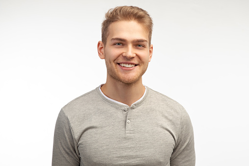 Portrait of enthusiastic man, smiles broadly, laugh joyfully at funny rumor, wears casual clothes. Content student has break after classes indoor. Isolated on white background.