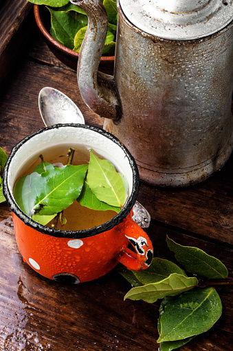 Delicious herbal tea with bay leaf on wooden background