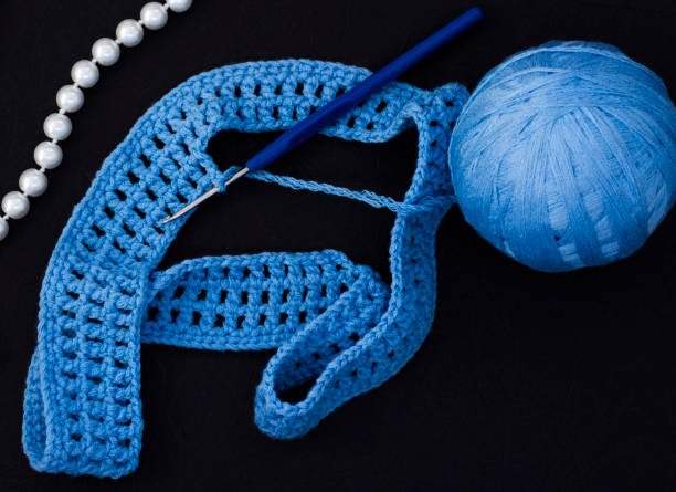 istock a ball of blue thread with a hook on a black background 1136968182