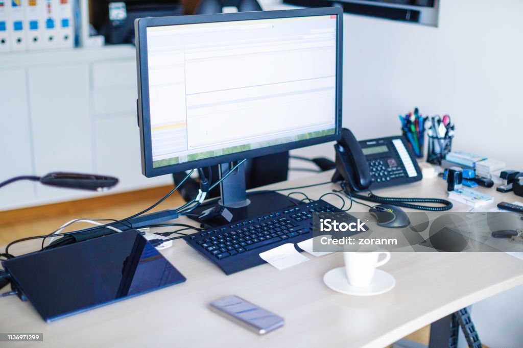Office desk with equipment Office desk with PC equipment, stationary, landline phone and mobile phone Desktop PC Stock Photo
