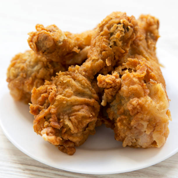istock Fried chicken drumsticks on a round white plate, side view. Close-up. 1136973897