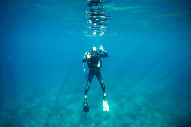 Scuba diver balancing while preparing for diving under the sea surface