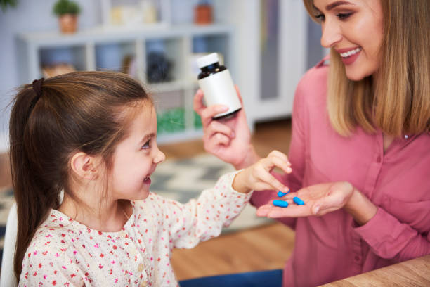 młoda mama daje jej córeczkę lek - vitamin pill pill medicine healthcare and medicine zdjęcia i obrazy z banku zdjęć