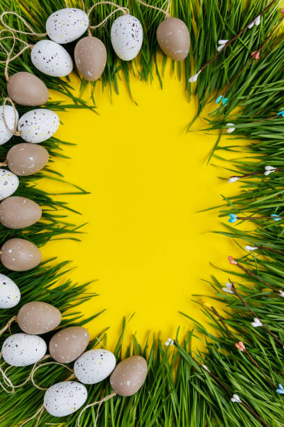 istock Easter decor. Decorative eggs and green grass are laid out on a yellow background 1136975629