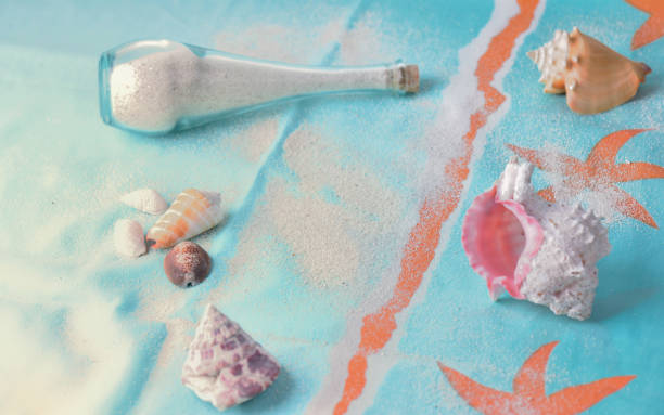 sand in a little bottle and tropical seashells on a beach towel