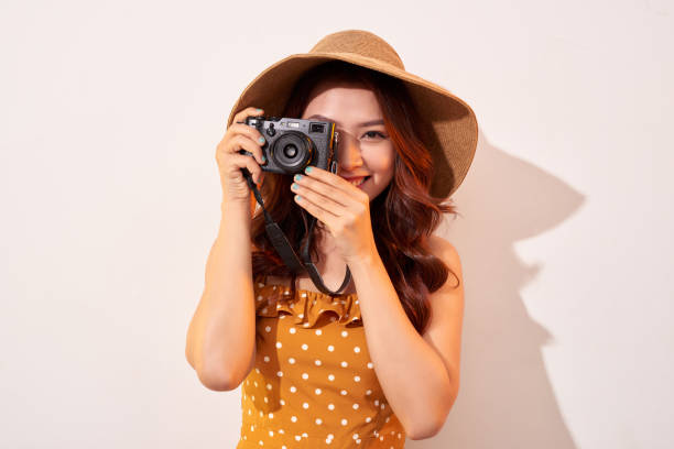 istock Woman traveler with a camera, beige background 1136981114