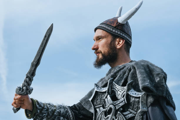 istock Low Angle View Of Man In Costume Holding Sword Against Sky 1136984598