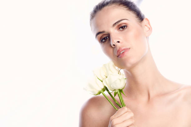 A young woman receives a single cream rose. She has her eyes closed as she takes in the beautiful scent of the rose