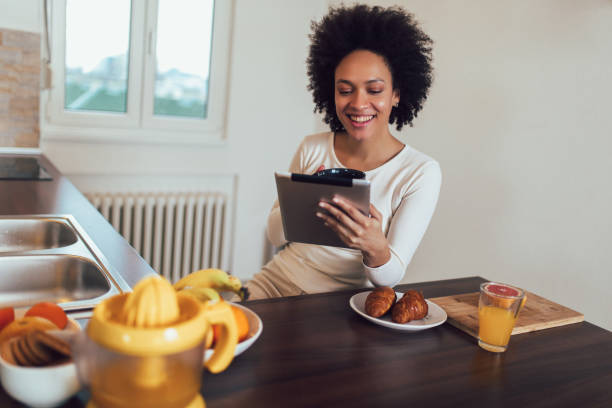 istock Smiling young African female using tablet in kitchen 1136988826