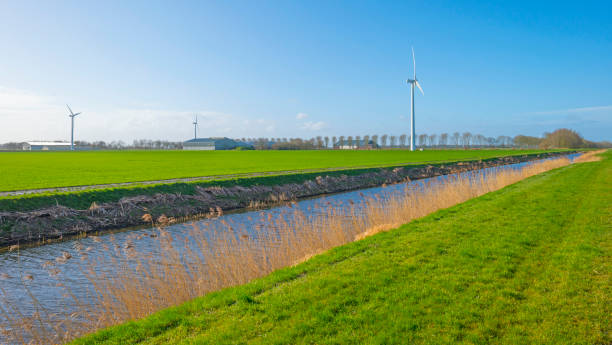 istock Canal in a field below a blue sky in winter seen from a dike 1136992468