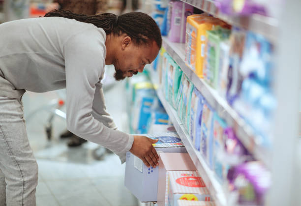 Single father buying diapers in supermarket Single father buying diapers in supermarket, picking up box of diapers adult diaper stock pictures, royalty-free photos & images