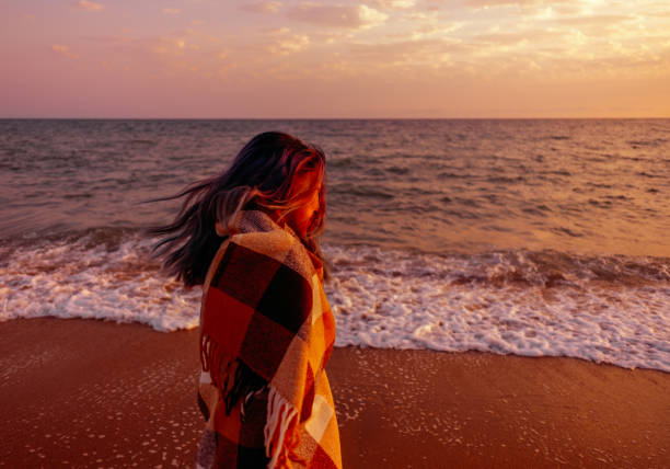 istock Woman walking on coast at sunset. 1136994327