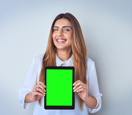 Portrait of an attractive young woman holding a digital tablet against a blue background