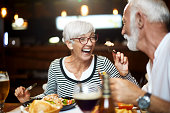 Senior couple feeding each other and having a good time during a meal in a restaurant