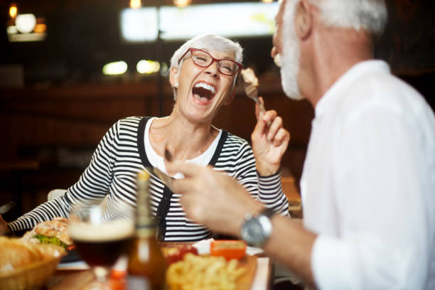 istock Elderly couple cheerfully feeding each other during a meal in a restaurant 1136997580