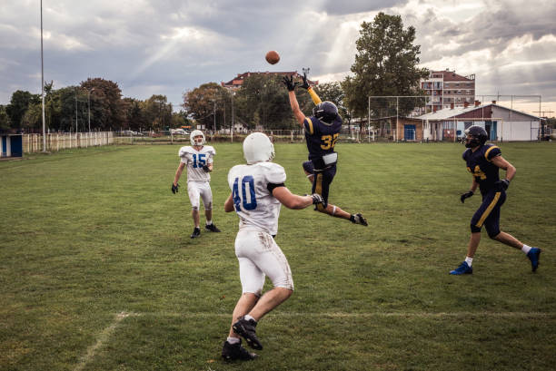 jogador de futebol americano determinado que trava a esfera em um fósforo no campo de jogo. - football player group of people running american football - fotografias e filmes do acervo