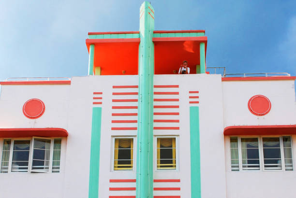 McAlpin Hotel Facade Miami, United States - October 10, 2014: McAlpin Hotel, designed by L. Murray Dixon, 1940, is located at Ocean Drive, in Miami Art Deco District.
The district is full of beautiful buildings in art deco style from the period between 1930-1942. The area located in South Beach, also known as Old Miami Beach Historic District is a well-visited tourist attraction with its 960 art deco historic buildings.
At the top of the building, an East Asian descent is making a peace sign to the camera 1 hotel south beach stock pictures, royalty-free photos & images