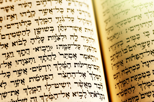 A Hebrew translation of the bible lies open with a gold tinge to the light.