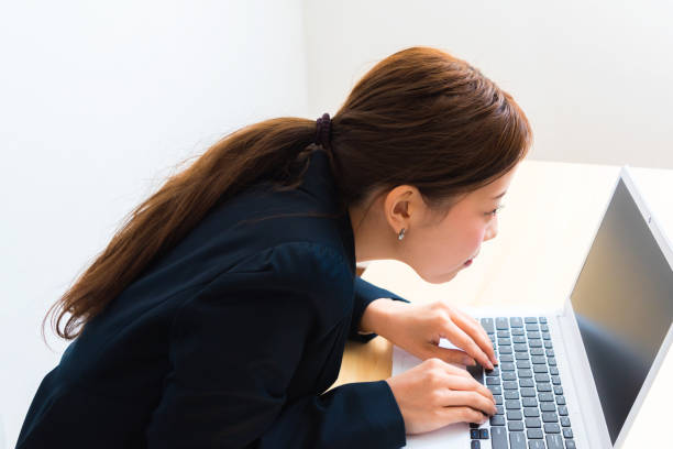机に座りながらノートパソコンを使う女性のイメージ - ねじれた ストックフォトと画像