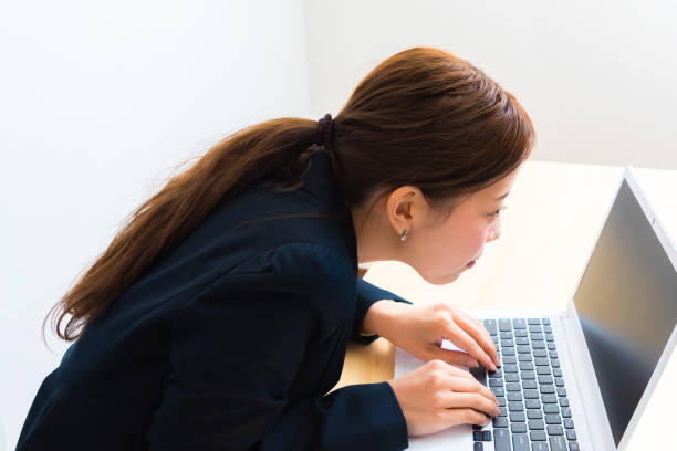 Image of woman using laptop while sitting at her desk Image of woman using laptop while sitting at her desk bad posture stock pictures, royalty-free photos & images