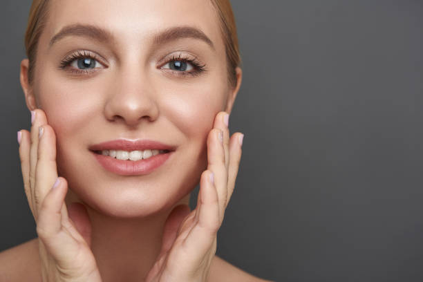 Glad woman touching her skin and smiling cheerfully