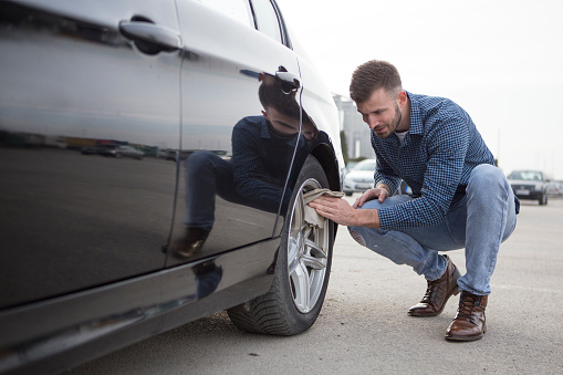 Mid adult man cleaning his car with a cleaning cloth. About 30 years old, Caucasian male.