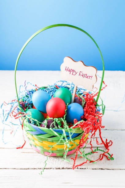 istock Image of basket with colorful eggs on empty blue background on wooden table 1137013321