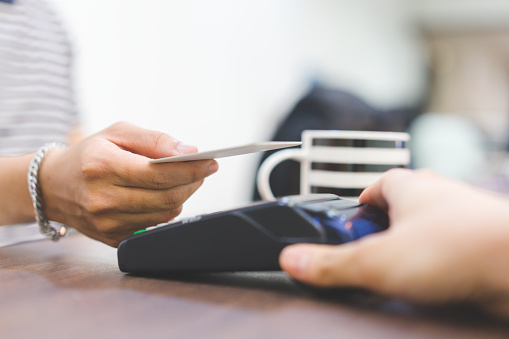 cerrar la mano del cliente utilizando la tarjeta de crédito para pagar la factura mediante el uso de la máquina de pago en la mesa en la cafetería, concepto de pago sin contacto photo