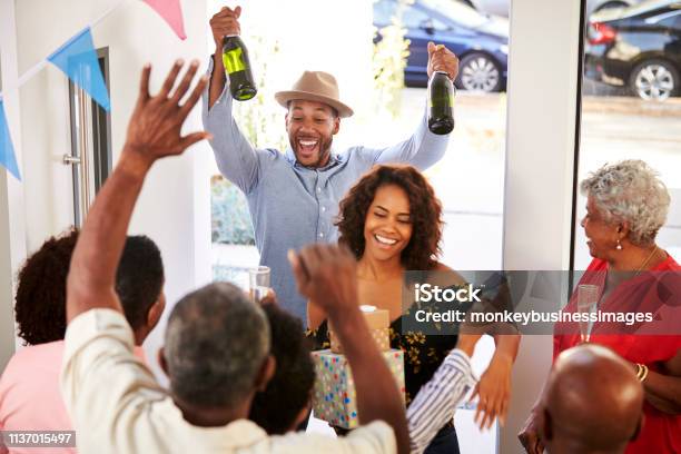 Three Generation Family Throwing A Surprise Party Welcoming Guests At The Front Doorelevated View Stock Photo - Download Image Now