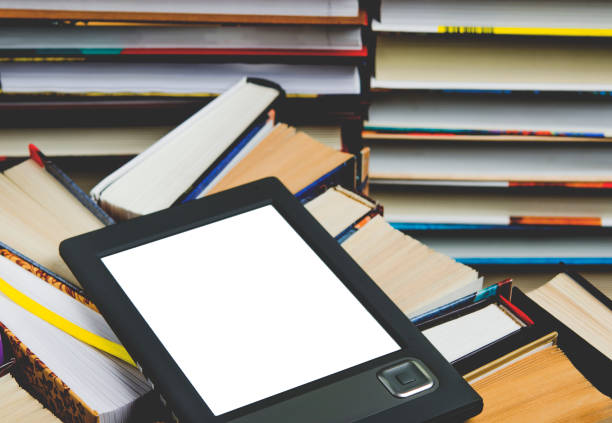 istock The e-book with a white screen lies on the open multi-colored books that lie on a dark background, close-up 1137015513