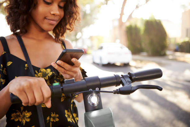 istock Millennial black woman standing on an electric scooter using smartphone,close up 1137015875