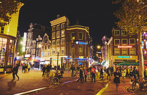 AMSTERDAM, NETHERLANDS - NOVEMBER 19, 2018: Restaurants, bars, cafes and coffeeshops on the streets in the city center at night.