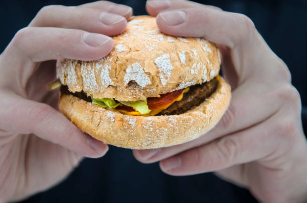 istock Men's hands keep a fresh juicy burger with tomato 1137018852
