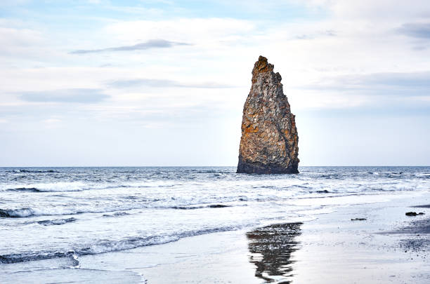 Rocky coast, cliff, Kunashir island, cloudy sky.