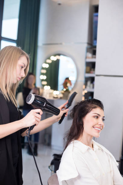 istock Blonde barber is blow-drying client's hair in hairdressing saloon 1137019708