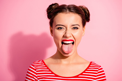 Close up photo beautiful amazing she her lady impolite careless pretty hairdo two buns bright pomade allure big lips tongue out mouth wear casual striped red white t-shirt isolated pink background.