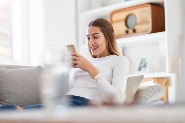 istock Young woman using her smartphone at home 1137020402