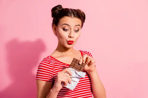 Photo of Close-up portrait of her she nice cute charming attractive lovely cheerful funny girl in striped t-shirt holding in hands snapping dessert air blow kiss isolated over pink pastel background